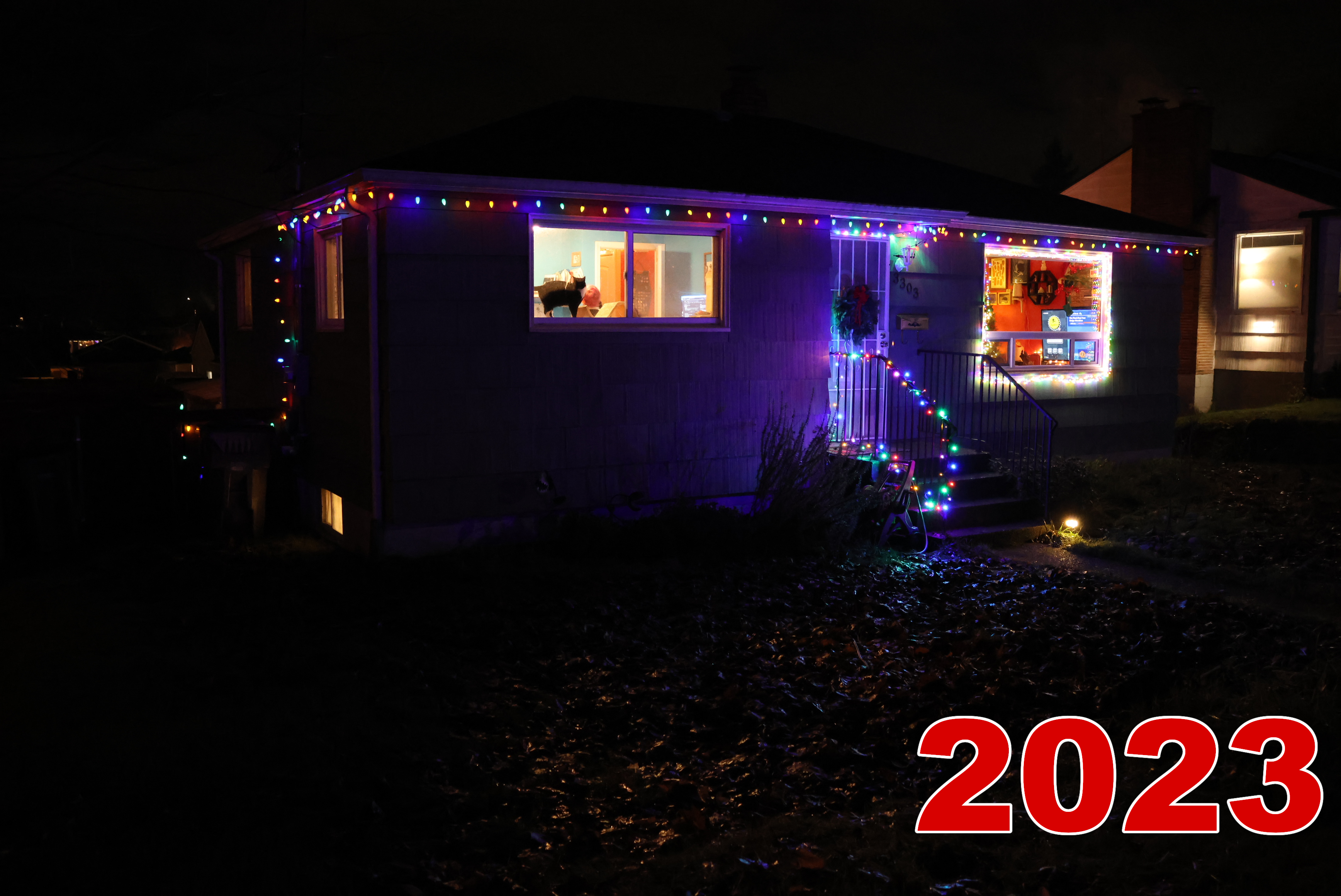 The exterior. It's quite dark out, so the christmas lights really stand out. We've added a few more lights to the basic set going along the trim. There's a new strand around the large window, and around the railing for the stairs. There's also a wreath on the door, and a cat in the window!