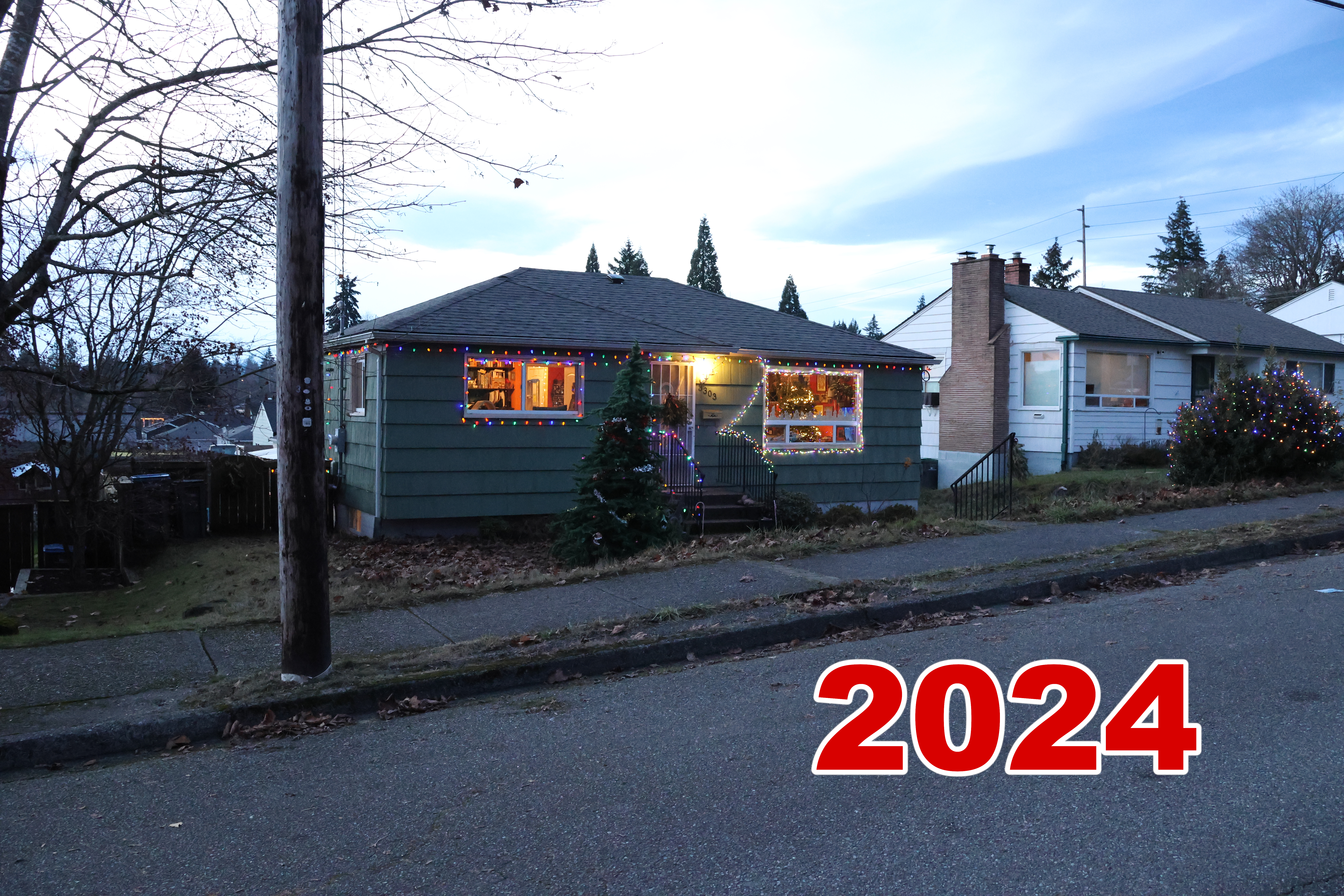 Exterior, taken shortly before sunset. We put up a fake tree in the front yard this year, and decoarted it with baubles and tinsel. We also have a nice net of lights on our big spiky bush.